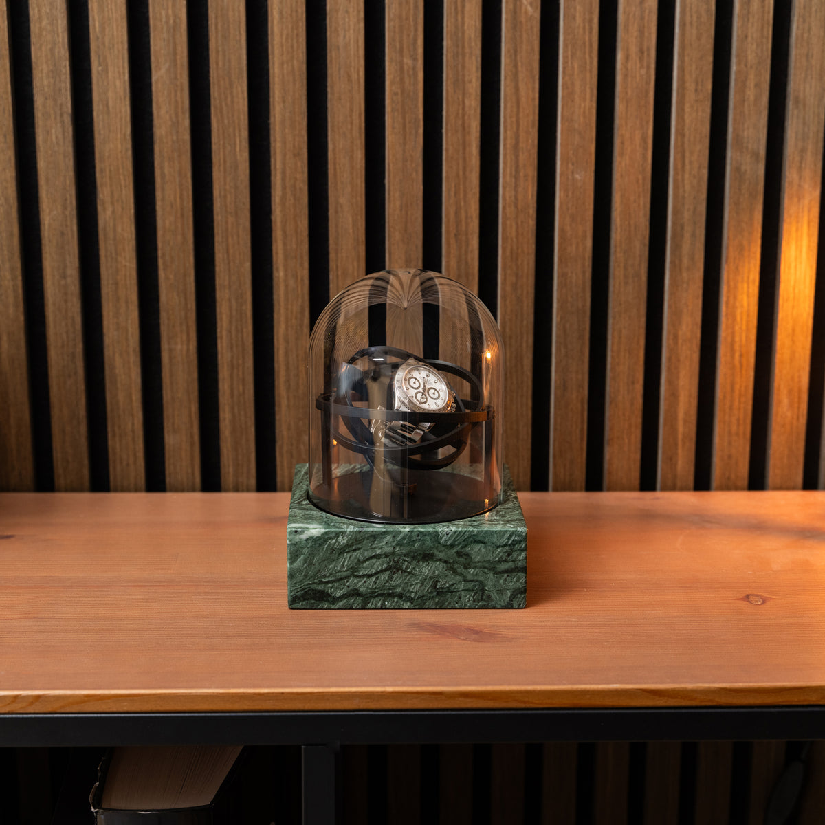 Front view of the green marble Orbital single watch winder holding a steel chronograph in black rings beneath a clear dome.