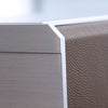 Close-up of the AUBLIQ watch box showing the brushed silver aluminium front, beveled corner and textured brown side panel.